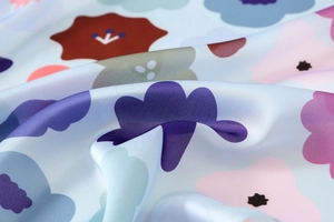Detalle del pañuelo de satén azul claro con motivos florales y nubes en varios colores