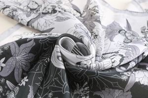 Detailed close-up of retro floral silk scarf with gold edges and smooth draped texture