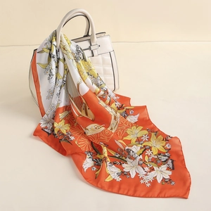 Detail of silk-like satin scarf with vibrant orange lily and butterfly floral patterns