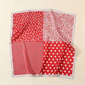 Dettaglio macro della sciarpa in seta rossa con motivo paisley, pois e bordi argentati