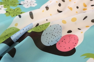 Détail rapproché d'un foulard en soie satinée avec motifs de lapin et fleurs colorées