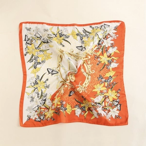 Detail view of square silk scarf featuring lily and harp prints with orange silk satin finish