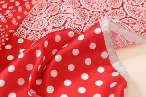 Dettaglio foulard in seta rossa con motivi paisley e pois con trama liscia effetto satinato