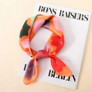 Pañuelo cuadrado de satén naranja vibrante con flores coloridas sobre revista de moda