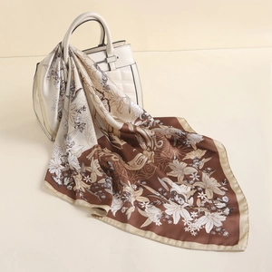 Close-up of silk scarf with floral patterns draped on a white textured handbag