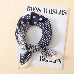 Dettaglio di un foulard in seta blu navy con pois bianchi e motivi paisley su una rivista