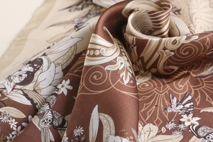 Detailed view of silk square scarf featuring butterfly prints and golden paisley patterns