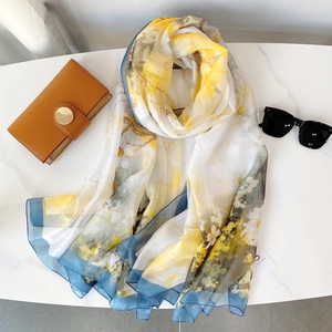 Détail d'un foulard à imprimé floral artistique avec bordure bleue sur marbre