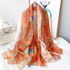 Vue détaillée d'un châle en mousseline orange à fleurs sur une chemise blanche d'été