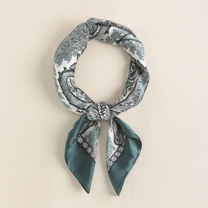 Close-up of silk-textured paisley square scarf tied in a neat neck knot detail