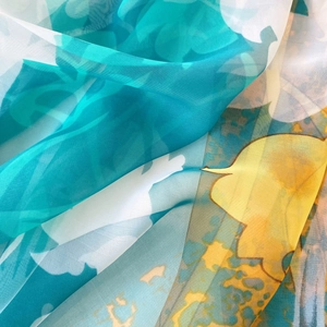Détail macro d'un châle en soie floral semi-transparent aux motifs artistiques bleus et jaunes