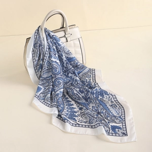 Blue and white paisley silk scarf draped elegantly on a quilted white luxury handbag