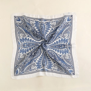 Detailed view of square silk scarf featuring blue paisley patterns and a satin finish