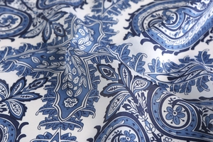 Detailed view of silk-like blue and white paisley pattern with gold trim edge fabric