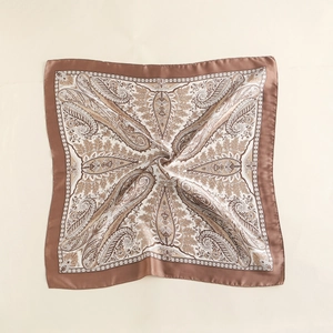 Detailed close-up of paisley pattern silk scarf with golden satin finish and elegant folds