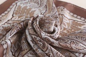 Macro detail of retro paisley silk scarf with gold trim and elegant brown floral patterns