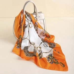Detail of silk satin scarf with orange paisley and equestrian motifs on a quilted bag