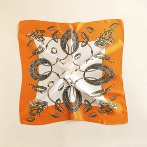 Close-up of retro orange silk scarf featuring elegant gold chain and jewelry patterns