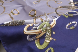 Macro detail of silk scarf showing vintage golden chain patterns and fine fabric texture