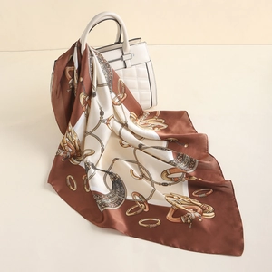 Detail of silk-like square scarf with gold chains and paisley motifs on a handbag