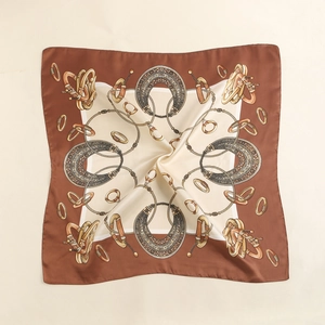 Detail view of retro silk scarf with horseshoe and golden chain pattern on fabric