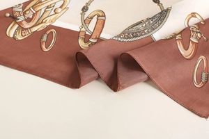Detailed close-up of silk scarf showing equestrian chain patterns and smooth texture