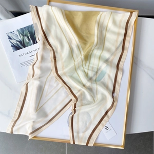 Detail view of lightweight geometric striped silk scarf on a white decorative tray