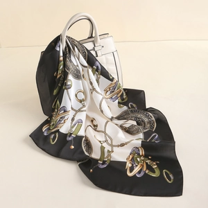 Close-up of vintage silk scarf with luxury gold chain and jewel patterns on handbag