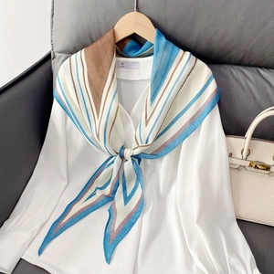 Geometric striped silk scarf in blue and brown styled on a white shirt collar