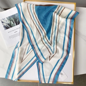 Detail of light blue geometric striped silk scarf on marble with brand tag