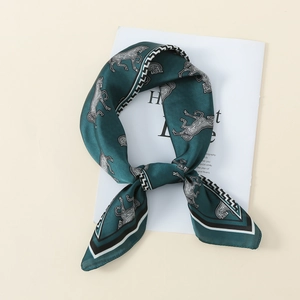 Detail of dark green silk scarf with horse print and geometric borders on magazine