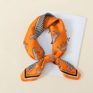 Detailed view of orange faux silk scarf with white horse print and wavy geometric borders