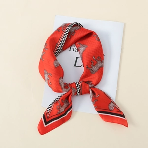 Detailed close-up of a red silk scarf with white horse pattern and geometric border
