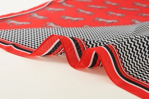 Close-up of red silk scarf featuring classic horse patterns and retro golden borders