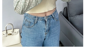 Detail view of light blue straight denim jeans with classic metal button closure and five-pockets
