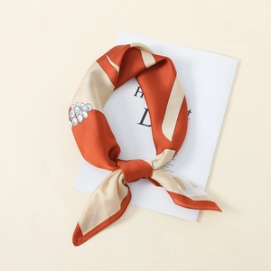 Detail of silk-like square scarf with orange geometric patterns and pearl dot print