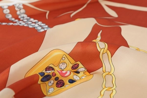Detailed macro view of luxurious silk scarf featuring vintage gold chain and jewel prints