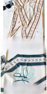 Detailed macro view of long silk scarves featuring refined edges and elegant letter patterns