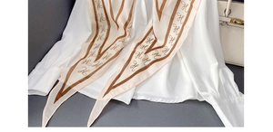 Detail of a white chiffon shirt with a brown H-pattern scarf and white textured bag