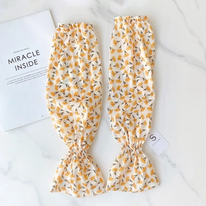 Close-up of floral chiffon sun protection sleeves with yellow daisies on marble background