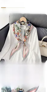 Détail d'un foulard en soie en forme de losange avec motifs floraux sur col blanc