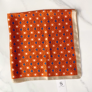 Detailed macro view of retro orange silk square scarf with golden satin border and patterns