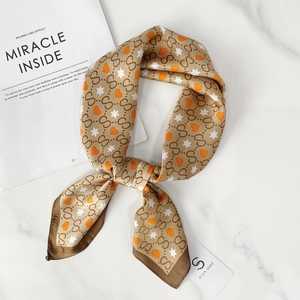 Detailed flat lay of silk-like scarf with S-letter pattern and orange hearts