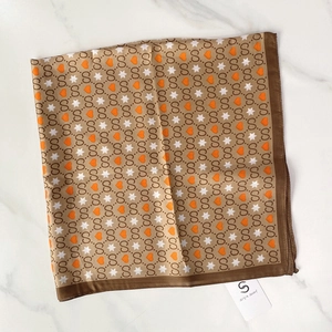 Close-up of a vintage square silk scarf featuring a gold border and paisley floral patterns