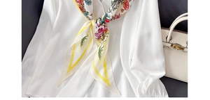 Détail d'un foulard en soie à fleurs avec lettrage China sur un col de chemise blanc