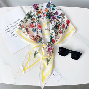 Vue détaillée d'un foulard en soie à fleurs avec rayures jaunes sur marbre