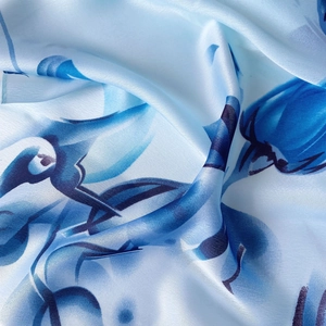 Elegant light blue silk scarf with dark blue magnolia floral print shown in soft folds