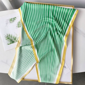 Detail view of green and white striped silk scarf with yellow borders in a gold frame