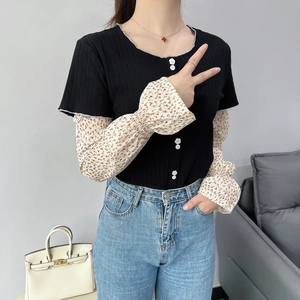 Detail of floral chiffon patchwork sleeve on black knit top with flower buttons