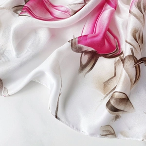 Detail showing the silky texture and elegant pink floral pattern on a white scarf